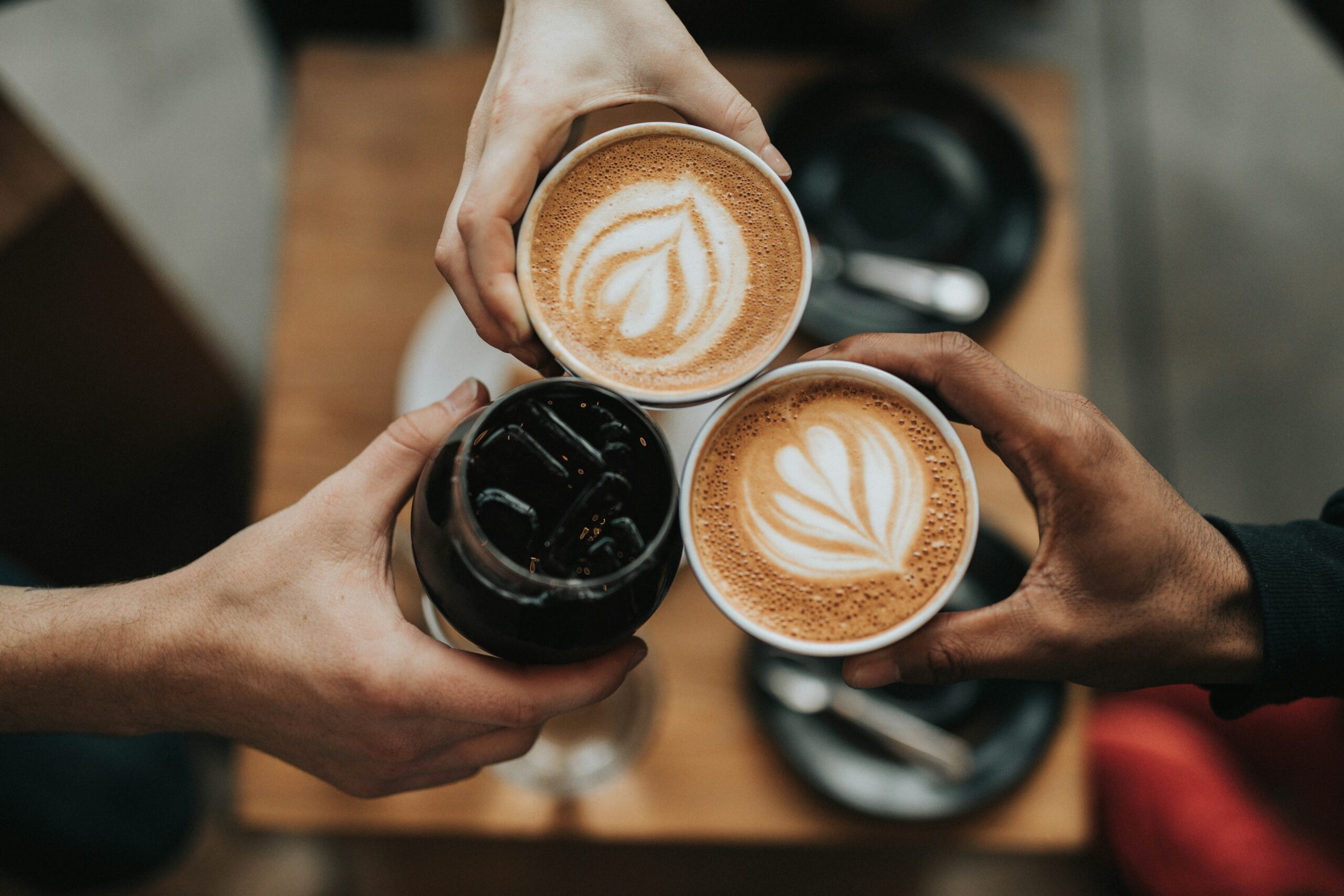 Enjoying Coffee, three people with two lattes and one ice Coffee